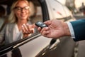 Buying new car. Young beautiful woman getting the car key while sitting in her new car Royalty Free Stock Photo