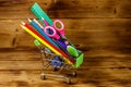 Buying school supplies. Shopping cart with school supplies on wooden background. Back to school concept Royalty Free Stock Photo