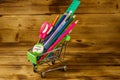 Buying school supplies. Shopping cart with school supplies on a wooden background. Back to school concept Royalty Free Stock Photo