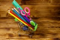 Buying school supplies. Shopping cart with school supplies on a wooden background. Back to school concept Royalty Free Stock Photo