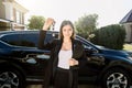 Buying or selling a car. Pretty young woman holding the keys standing in front of new black car crossover outdoors. Royalty Free Stock Photo