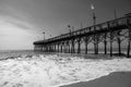 BW Pier on the Atlantic Ocean with waves crashing the beach - Black and White Royalty Free Stock Photo