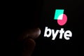 Byte app logo on the dark touch screen and finger is pointing at it. Byte new social media platform competitor to Tik