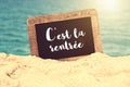 C`est la rentrÃÂ©e meaning Back to school written on a vintage chalkboard in the sand of a beach Royalty Free Stock Photo