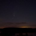 C / 2020 F3 comet NEOWISE at sunset. Landscape with wheat field and bales on horizon with a tree silhouette. At night Royalty Free Stock Photo