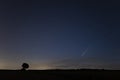 C / 2020 F3 comet NEOWISE at sunset. Landscape with wheat field and bales on horizon with a tree silhouette. Royalty Free Stock Photo