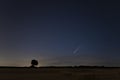 C / 2020 F3 comet NEOWISE at sunset. Landscape with wheat field and bales on horizon with a tree silhouette. Royalty Free Stock Photo