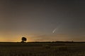 C / 2020 F3 comet NEOWISE at sunset. Landscape with wheat field and bales on horizon with a tree silhouette. Royalty Free Stock Photo