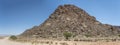 C13 gravel road and Dolerite boulders butte in Naukluft desert, north of Aus, Namibia