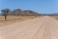 C27 gravel road and Dolerite boulders butte in Naukluft desert, west of Helmeringhausen, Namibia