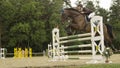 LOW ANGLE: Girl guiding her stallion over fence during show jumping competition.