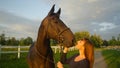 CLOSE UP: Young woman holds her stallion by the reins and pets him on the muzzle