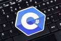 C#, C sharp programming language symbol, logo sticker, laying on a laptop keyboard, object closeup. Microsoft coding language
