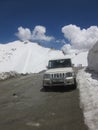 a cab on highway road passing through the hills and snow covered peaks in Leh, India