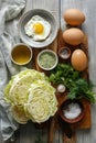 Cabbage heads, eggs, and herbs laid out on a wooden surface.