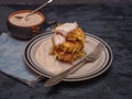 Cabbage oladi with sour cream, a cup with stewed sour cream on a dark wooden table, denim napkin, cutlery