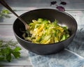 Cabbage salad with cucumbers and herbs in a deep black plate on a denim napkin and a turquoise wooden tray, coarse salt