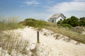 Cabin cottage small house on ocean seashore in grass and sand on a bight sunny day