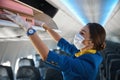 Cabin crew member shoving suitcase to overhead bin Royalty Free Stock Photo