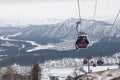 Cabin of a gondola cableway suspended on a rope in the Altai mountains with snow and fog sky on winter sunset. Ski resorts and