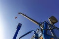 Cabin and hydraulic boom of crane with hook against blue sky.