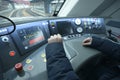 At the cabin of the passenger train. Train driver sitting in front of the dashboard and putting hand on start lever