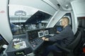 At the cabin of the passenger train. Train driver sitting in front of the dashboard and putting hand on a start lever Royalty Free Stock Photo