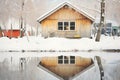 cabin reflected in a frozen pond edged with snow