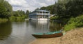Cabin by the river with a small boat docked on the sandy shore in a tranquil natural setting Royalty Free Stock Photo