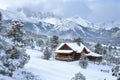 A cabin sits nestled in the snow-covered mountains, surrounded by pristine white snow, A cozy cabin nestled in snowy mountains, Royalty Free Stock Photo