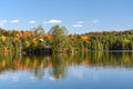 Lake surrounded by dense colourful forest during autumn colours season Royalty Free Stock Photo