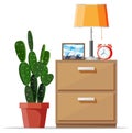 Cabinet with lamp, clock, picture frame and plant.