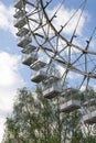 Cabins of Ferris wheel against a cloudy sky. Near a birch tree. Spring day in the park. Royalty Free Stock Photo