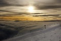 Cable car with chairs above the clouds during sunset, darkness deepens below