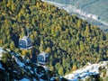 Cable car descends from a snowy mountain slope into a green valley with a ski resort