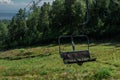 cable car empty seat among trees, grass field in green forest on hill, sunny summer blue sky with white clounds, baikal lake Royalty Free Stock Photo