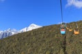 Cable Car on foreground with some tourists inside and Jade Dragon Snow Mountain