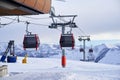 Cable car gondola at ski resort with snowy mountains on background. Modern ski lift with funitels and supporting towers Royalty Free Stock Photo