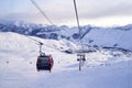 Cable car gondola at ski resort with snowy mountains on background. Modern ski lift with funitels and supporting towers Royalty Free Stock Photo