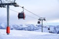 Cable car gondola at ski resort with snowy mountains on background. Modern ski lift with funitels and supporting towers Royalty Free Stock Photo