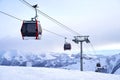 Cable car gondola at ski resort with snowy mountains on background. Modern ski lift with funitels and supporting towers Royalty Free Stock Photo