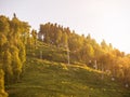 Cable car on a green slope illuminated by the sun at sunset