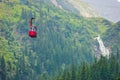 Cable car with green woods and Balea Cascada waterfall