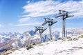 Cable car with lifting mechanisms in the snow-capped mountains on a clear sunny day against the backdrop of a blue cloudy sky.