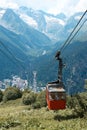 Cable car in the mountains, grass and mountains with glaciers, alpine meadows, village in the mountains