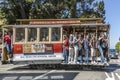 The Cable Car passes the Powell street in rush hour full of passengers standing also on the footboard in San Francisco, USA