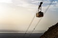 Cable car with people going down on funicular over mountains in Judean desert at the Dead sea background. Scenic view of the cable