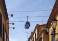 Cable car running directly above the rooftops of a street in the city center of funchal madeira with a blue sky