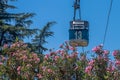 Cable car situated above trees and bushes with pink flowers