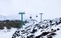 Cable car to Mount Etna national park in winter. View of volcanic terrain with black volcanic lava stones and snow under Royalty Free Stock Photo